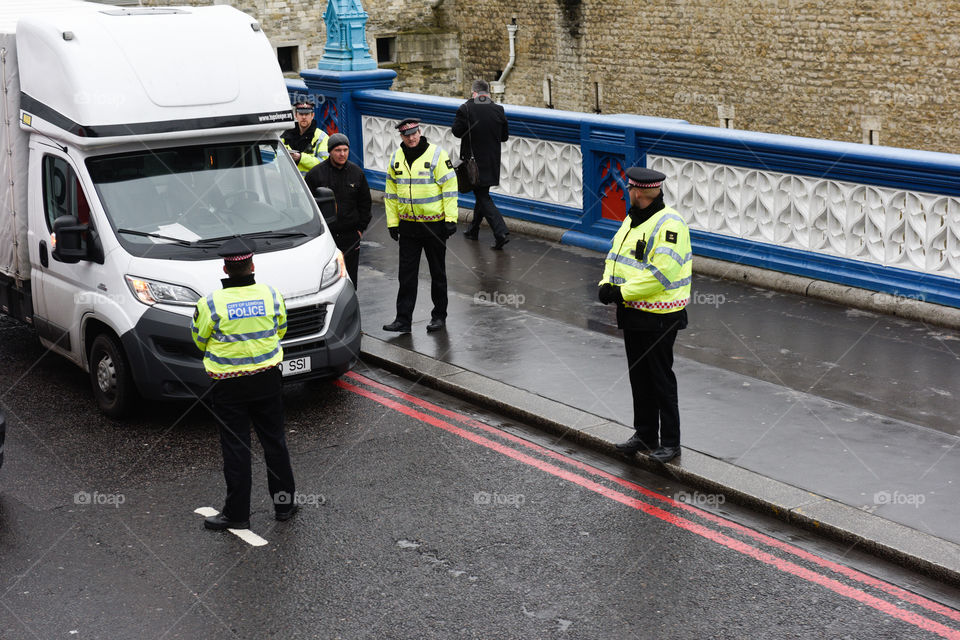 London Police is stopping a car in the traffic at Tower bridge.