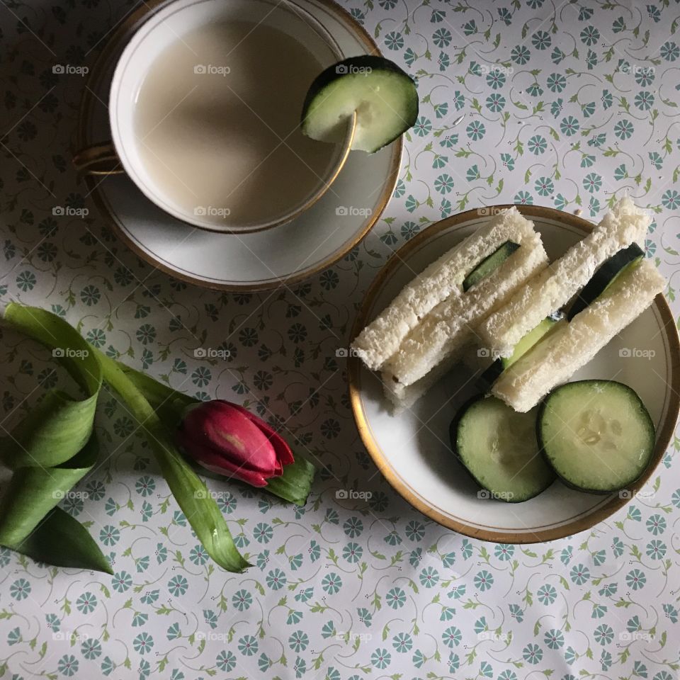 A delicious and healthy cucumber sandwich for lunch served next to a teacup and a pink tulip on a floral background. USA, America