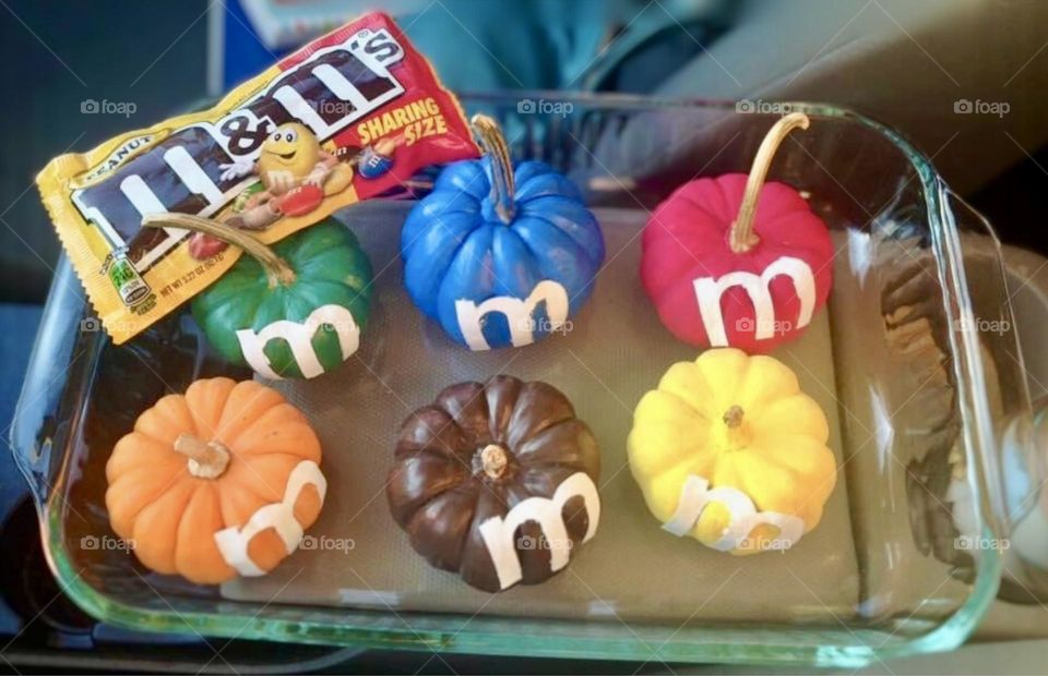 M&M pumpkins in green, blue, red, yellow, orange, and brown with a package of peanut M&M’s. 