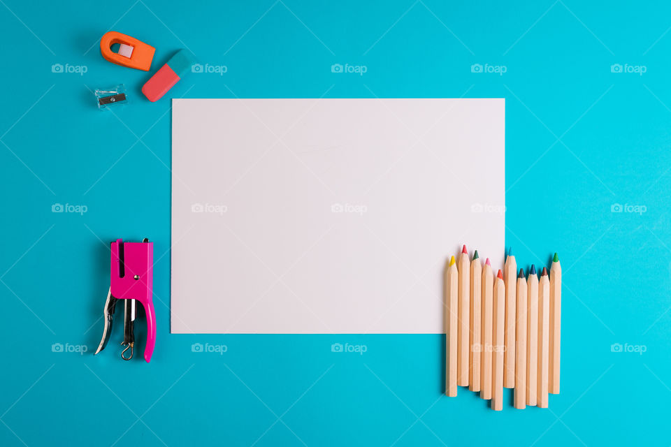 White sheet with school items on a blue background. Top view. Copy space