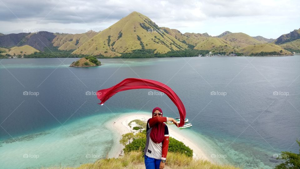 Woman waving red scarf at coastline