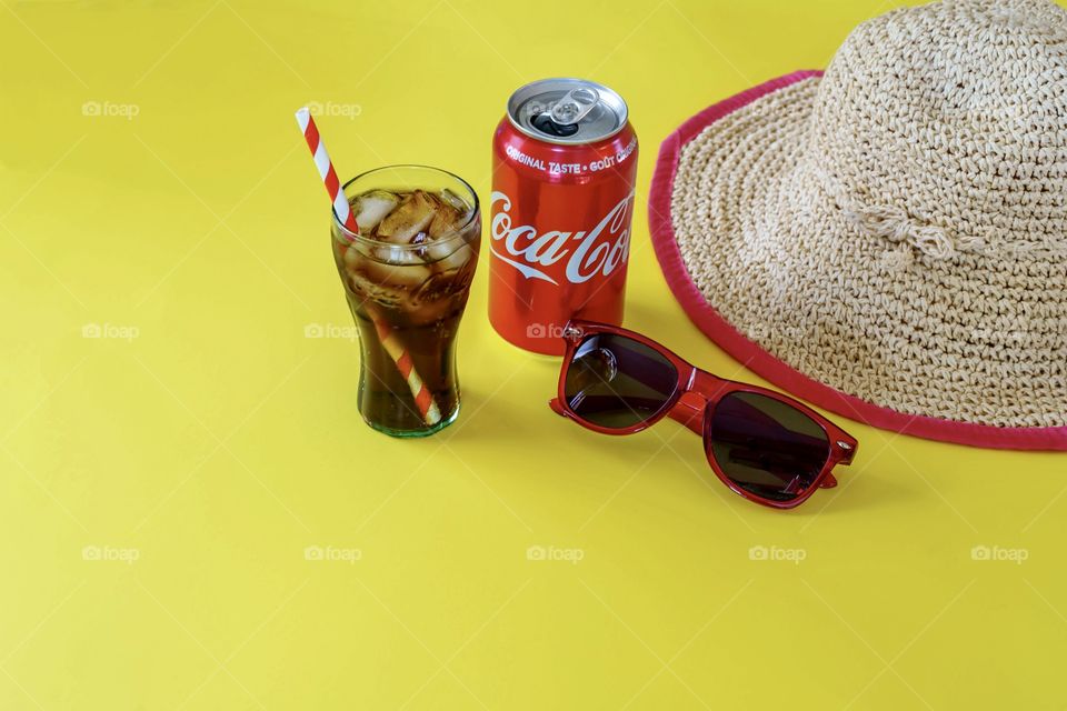 Coca Cola with summer hat, glasses and icy drinking glass 