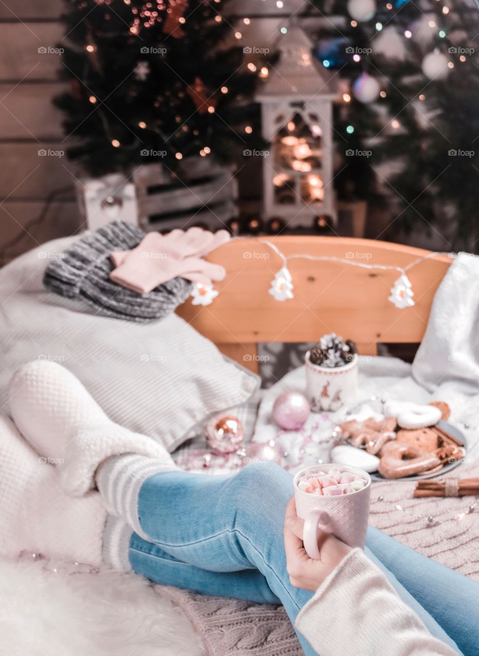 Cup with marshmallows in female hands on a background of Christmas decor