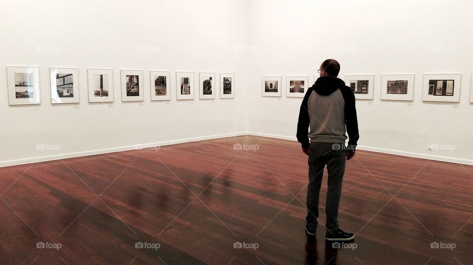 Man looking at photographs in art gallery