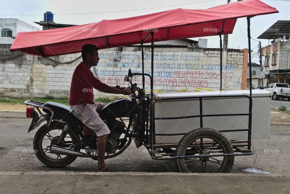 Man on his motorbike-tricycle hybrid transport makes sales on the streets