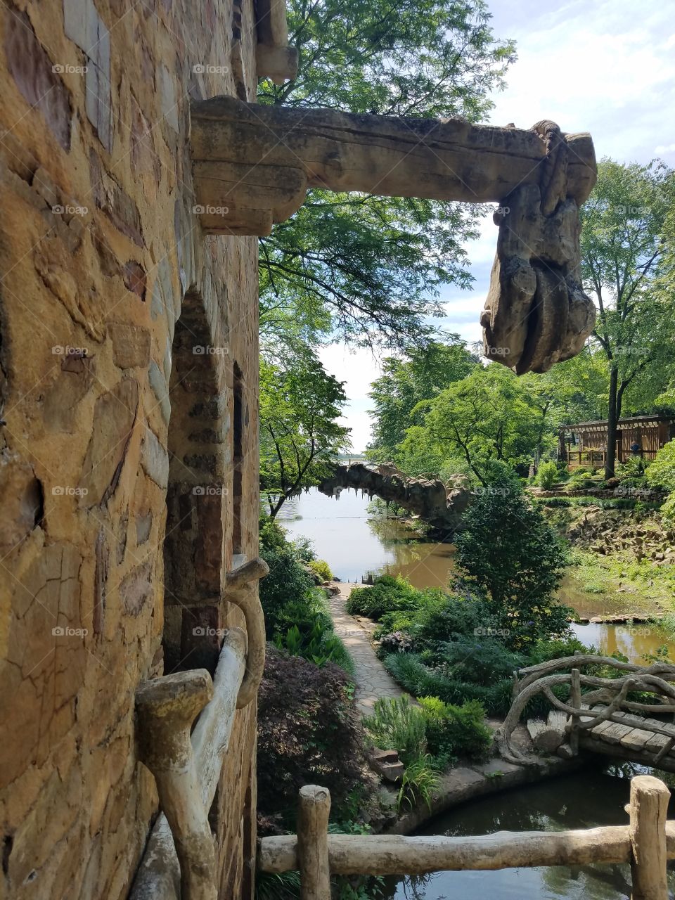 Urban garden with restored water wheel surrounded by spring plants and pond