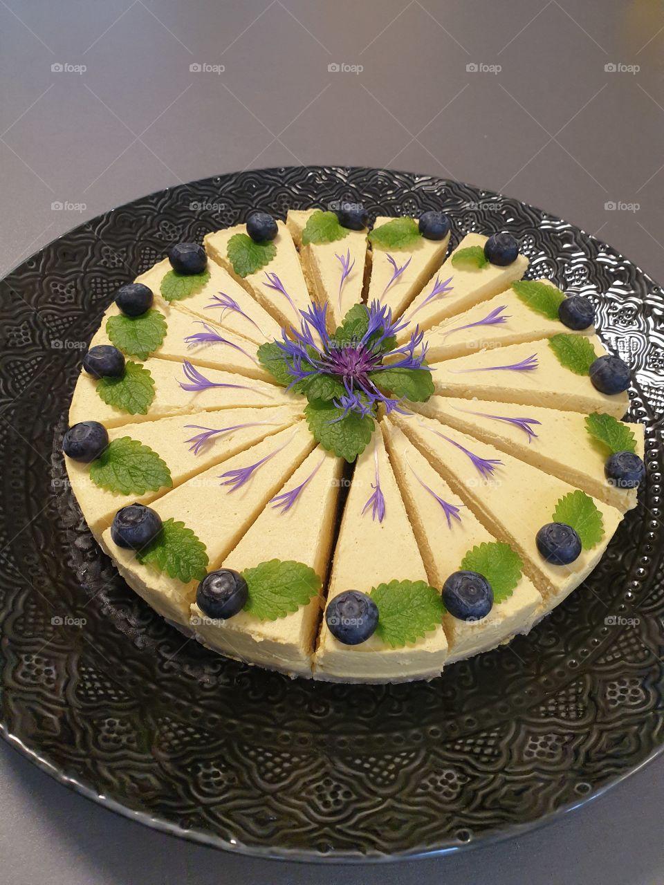 Raw vegan cake decorated with bluberries and flowers.