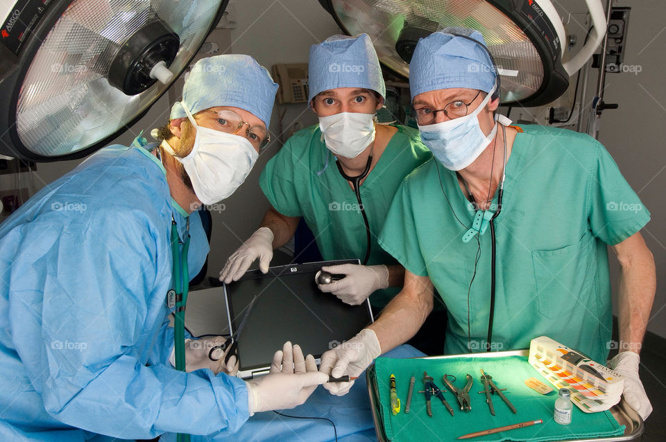 Three men operate on a computer in an emergency room at the hospital