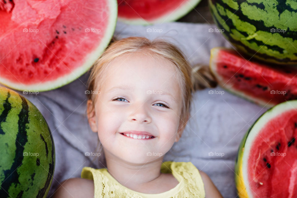 Cute little girl with blonde hair and watermelons 