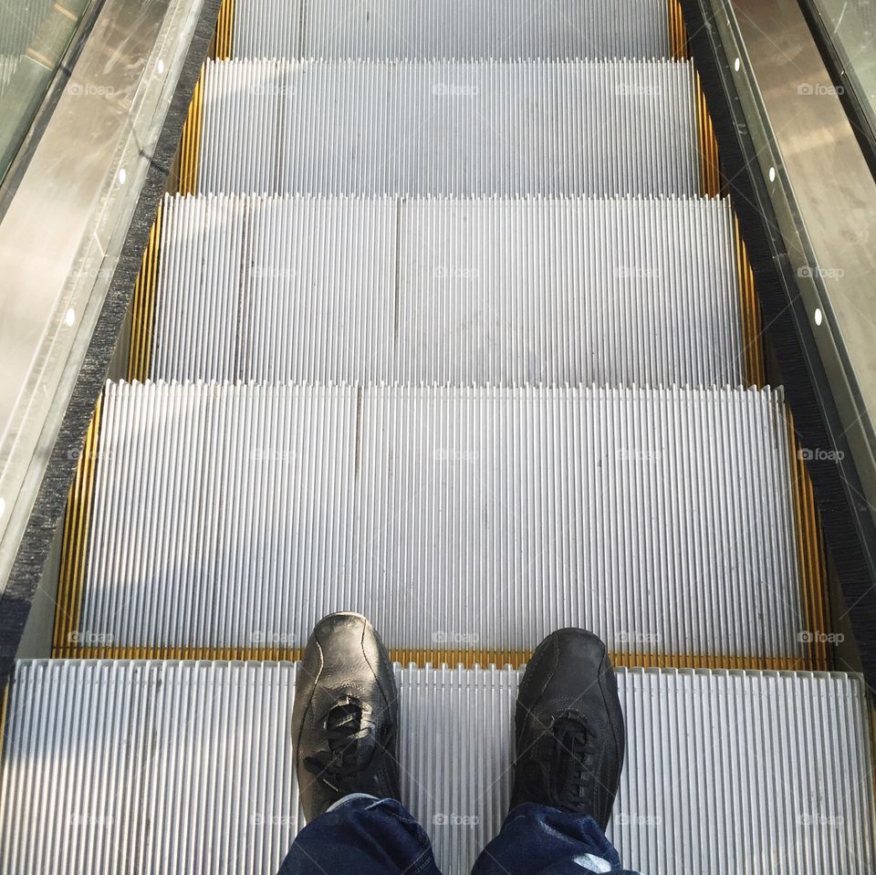 Low section of person standing on escalator