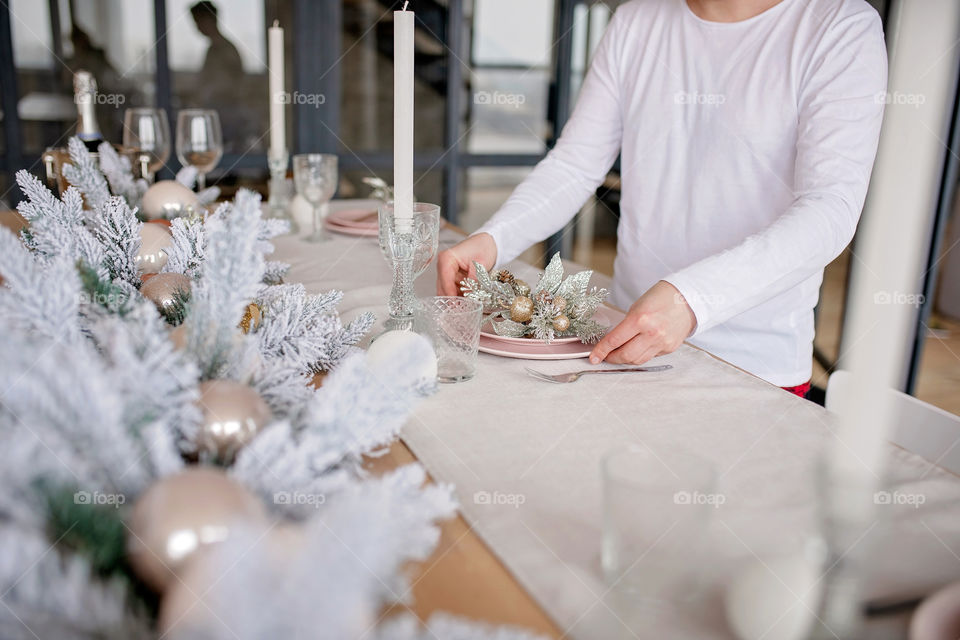 man sets a beautiful decorated winter table for a festive dinner.  Merry Christmas and Happy New Year.