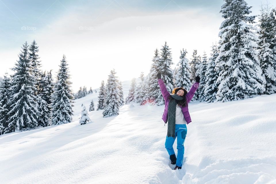 Woman being happy while in nature, in a beautiful snowy landscape.