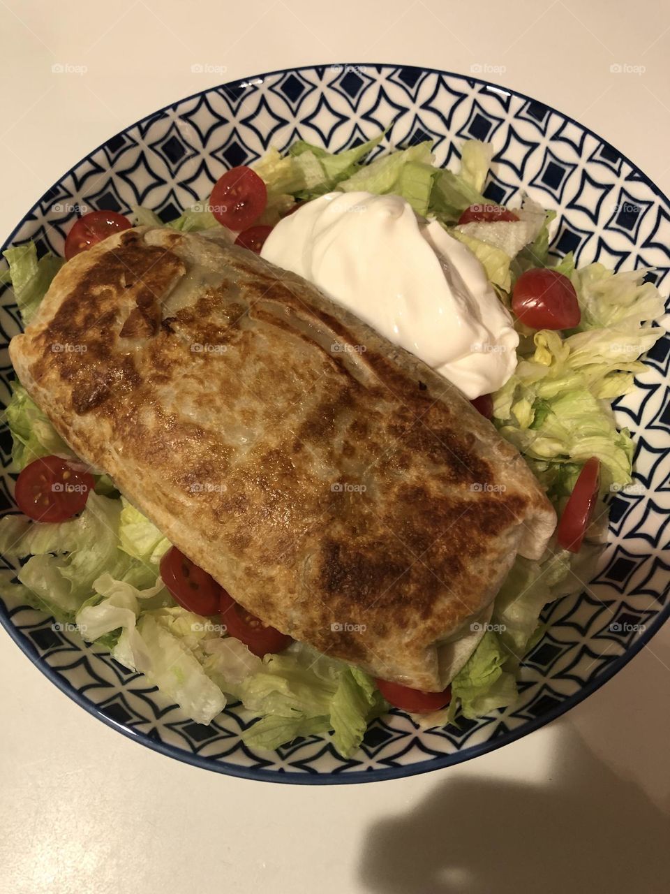 Home made burrito with salad and sour cream