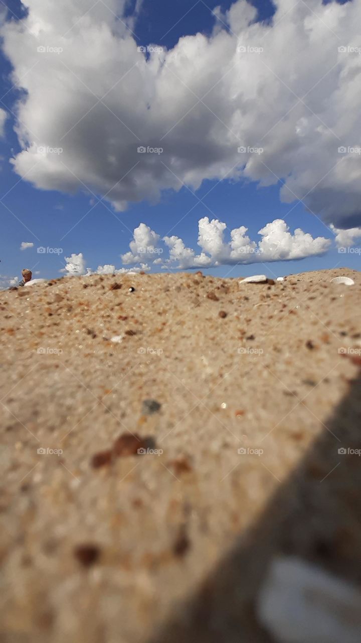 sand on the beach and white clouds on the blue sky view on the ground