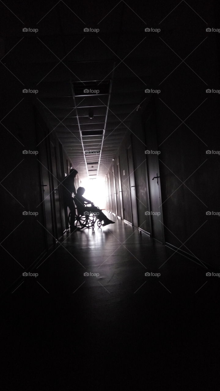 disabled woman on a wheelchair shiluette hallway backlight