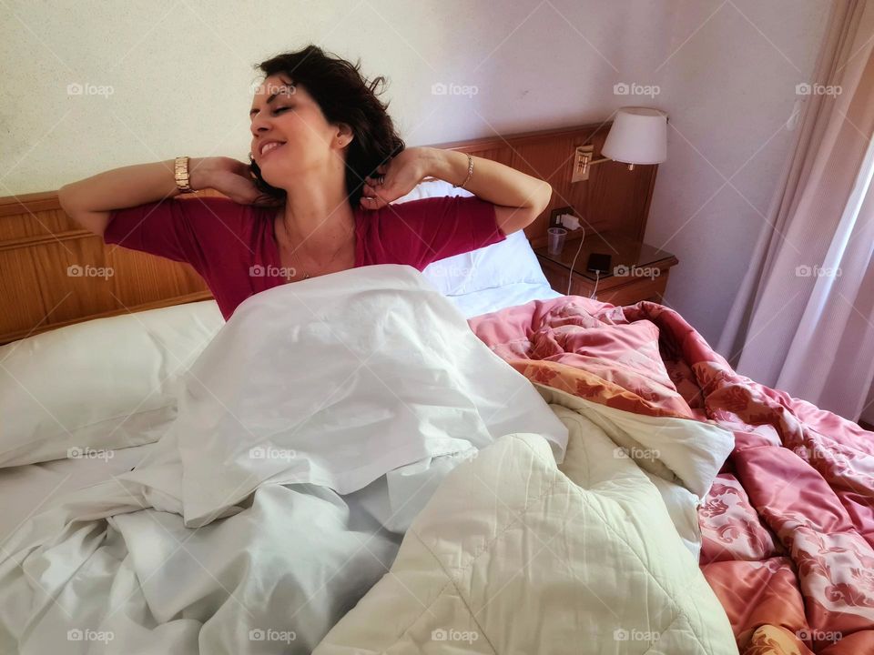 woman just woke up stretches in bed