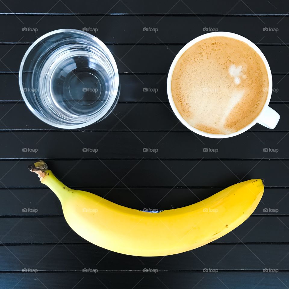 Breakfast: a cup of coffee, water and a banana, flatlay, smile