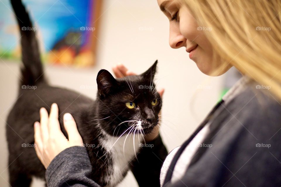 Authentic moment of connection celebrating the human and animal bond, young girl hugging tuxedo cat profile, view, smiling, sweet, candid moment