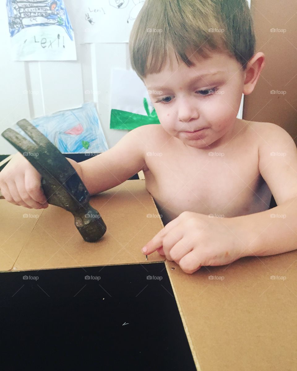 Shirtless boy holding hammer