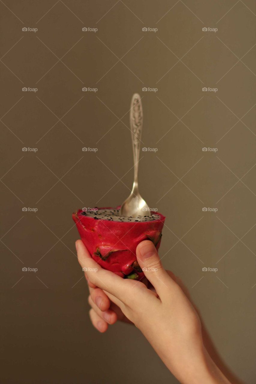 Dragon fruit with a teaspoon in a child's hand