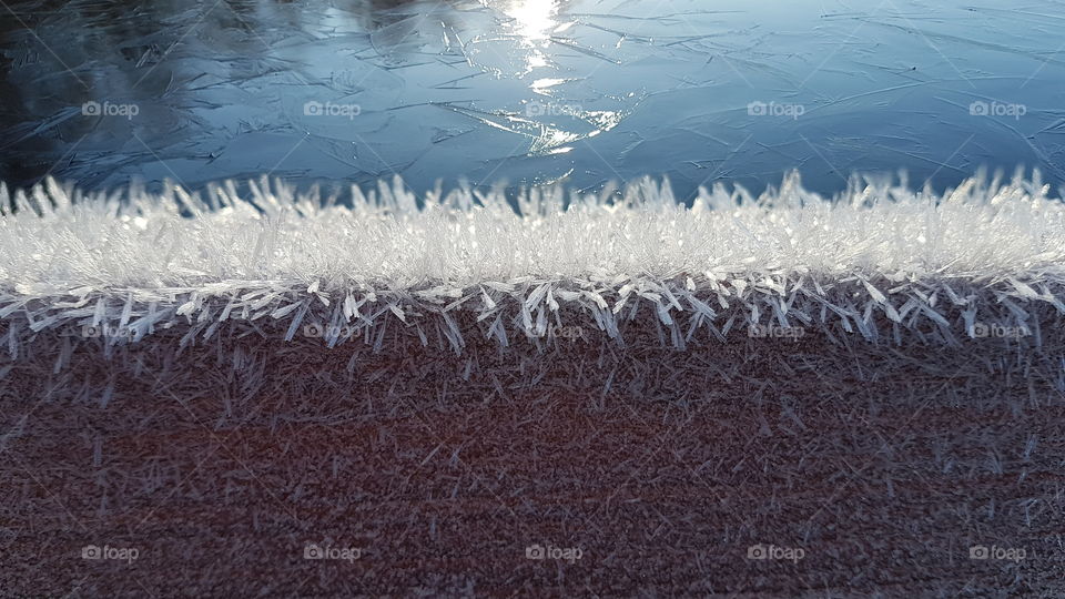 Beautiful frost on wood by the ice covered lake- vacker frost rimfrost på träyta vid sjö med is 