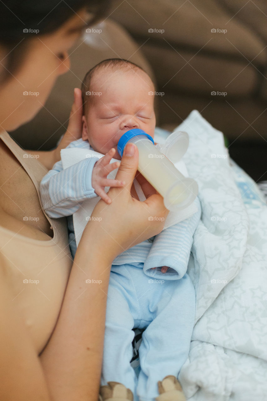 Mother feeding newborn baby from bottle 