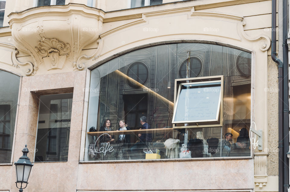People in a Munich cafe and reflections of the city on the glass