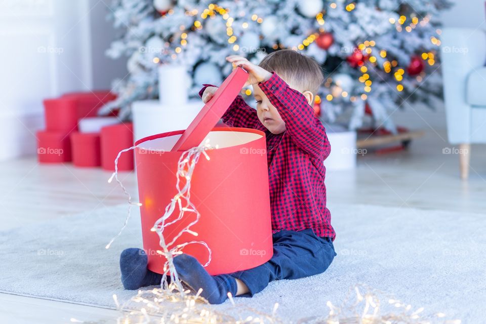 boy and gift box next to christmas tree