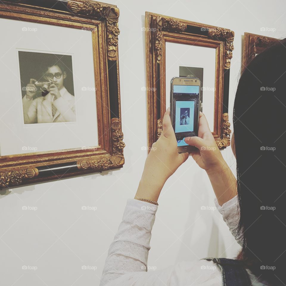 take picture of art print  in frame representing his majesty theBhumibol The great King of Thailand with phone