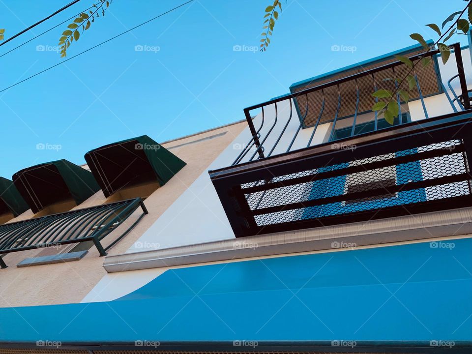 Architectural series of blue, white and beige historical building in downtown central eastern Florida town with European style with awnings, balconies, tropical trees and blue sky low angle.