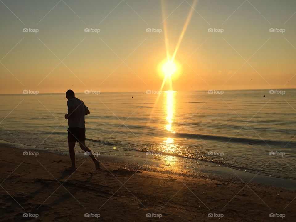 Man running on the beach in the sunshine