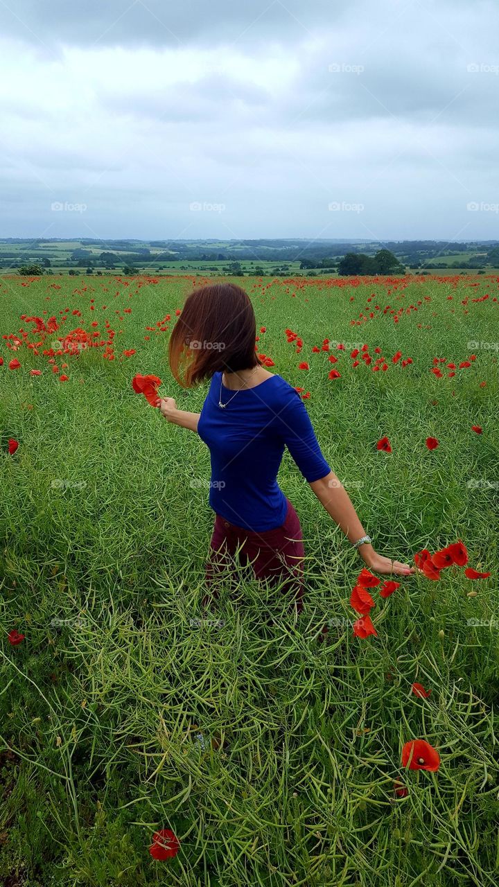 Woman in a field with poppy flowers. Wonderful scenery and beautiful nature. Without any filters and digital retouching.