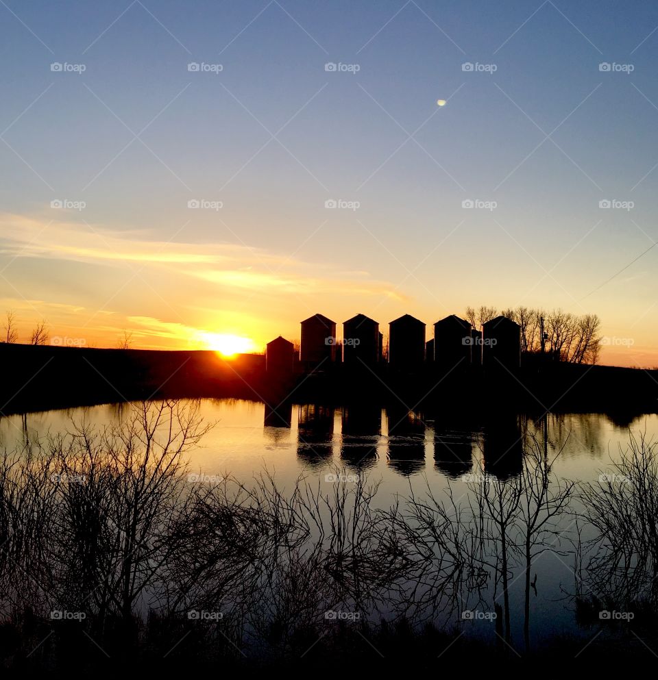 Grain bins reflecting on the water 