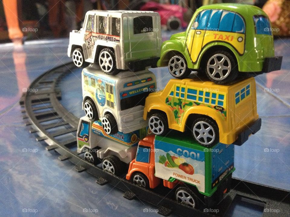 Colorful stacked toy cars on train rail