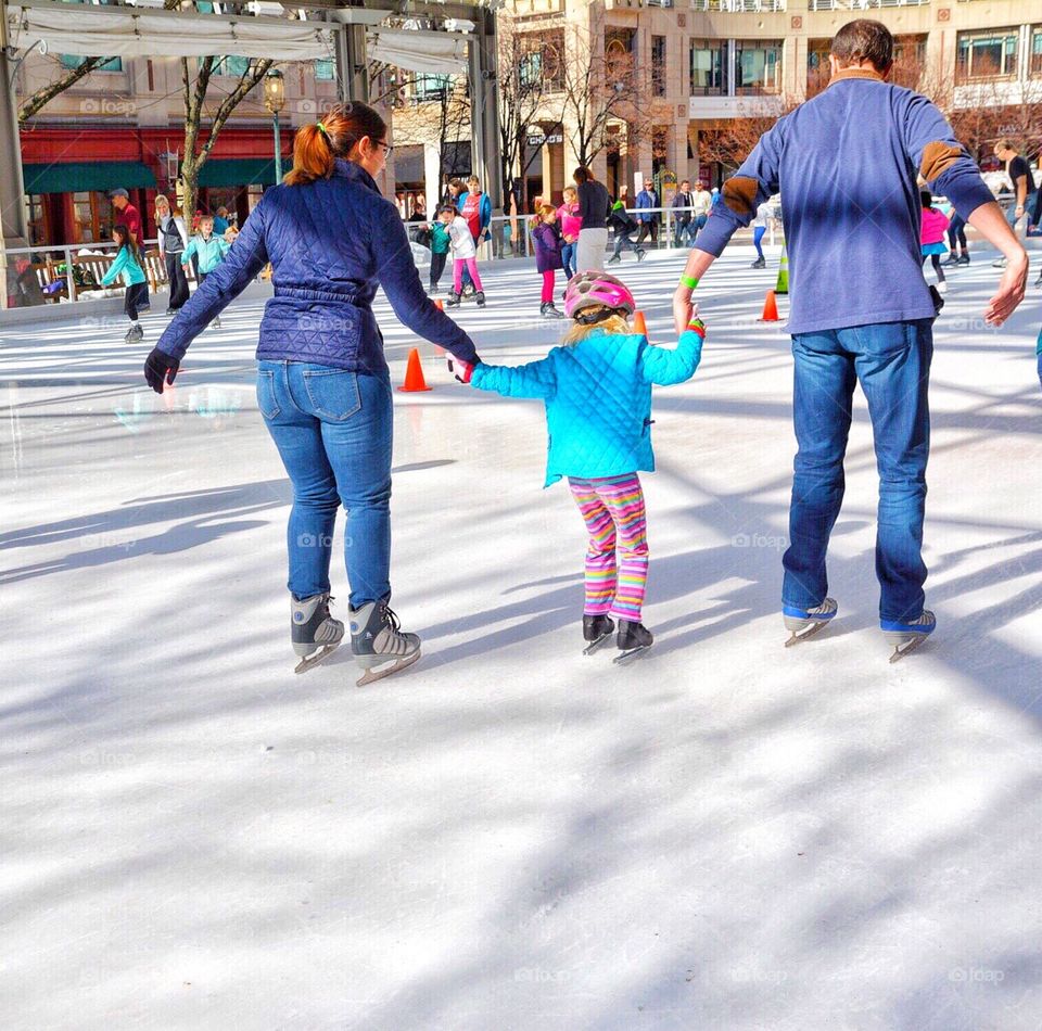 Parents teaching child to ice skate