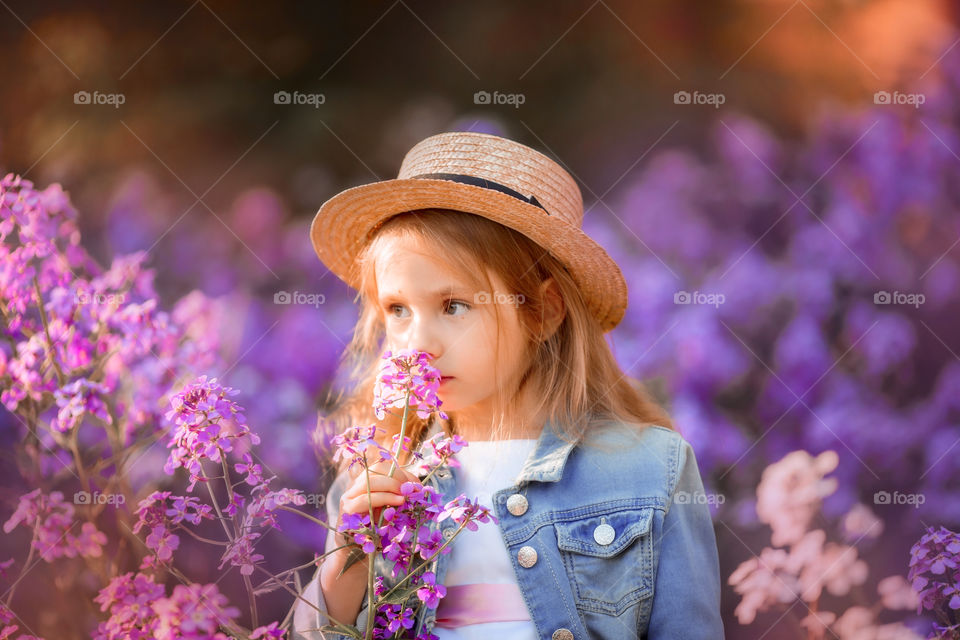 Cute little girl portrait in blossom meadow at sunset 