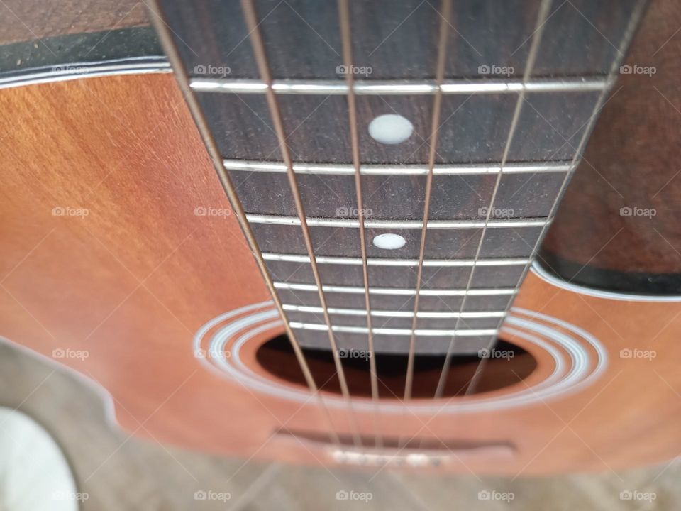 An acoustic guitar is a type of guitar where the sound produced comes from the vibration of the guitar strings that are channeled through the saddle and bridge where the strings are attached into the sound chamber