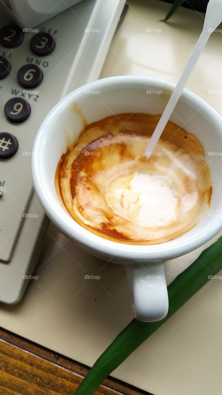 a cup of coffee next to the phone