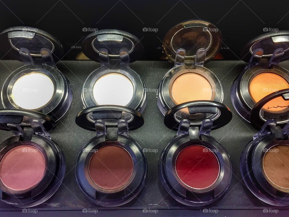 Tester compacts of blush, highlighter, and contour on display to try before buying at a beauty supply store.