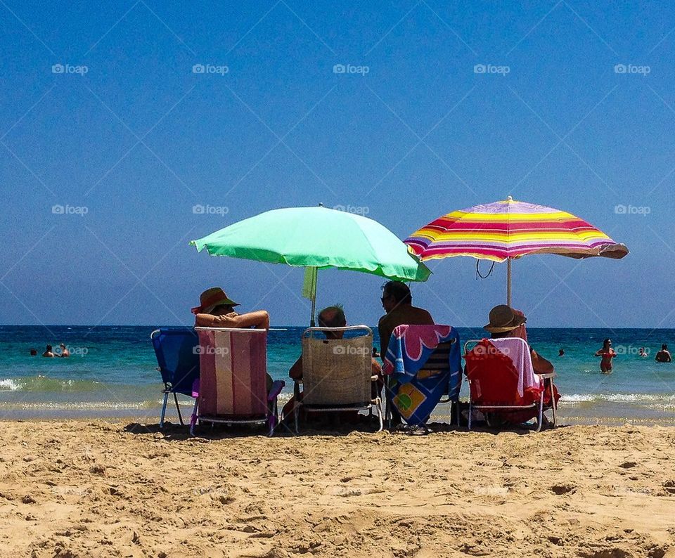 Summer vacation . People sitting under umbrellas on a sandy beach