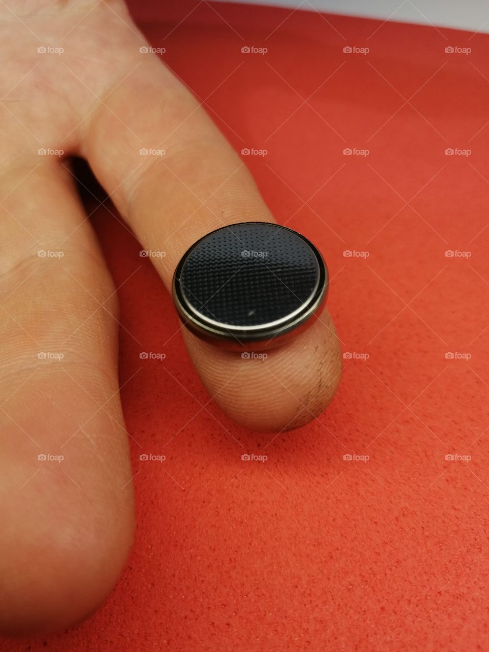 small new finger-type battery on a red background close-up