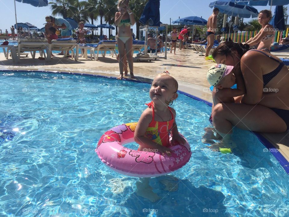 Маленькая девочка плавает с кругом в бассейне у отеля в путешествии На море Дети