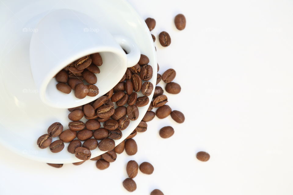 Some coffee beans falling from a cup