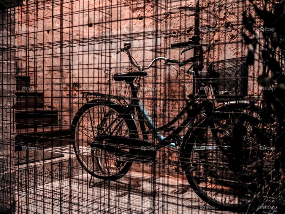 An old bicycle parked in the stairway behind steel cages