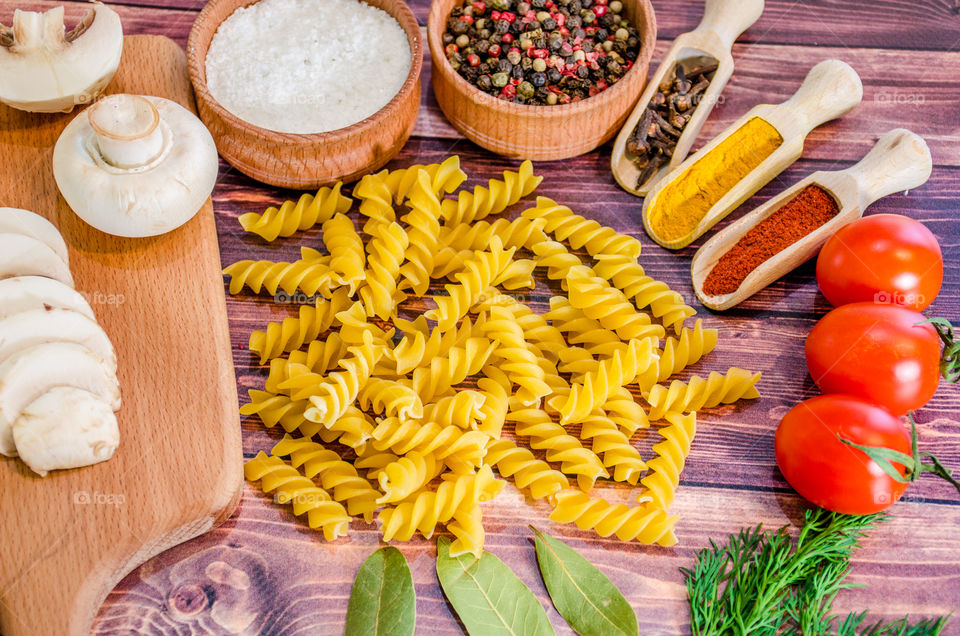 Raw pasta with ingredients and wooden accessories