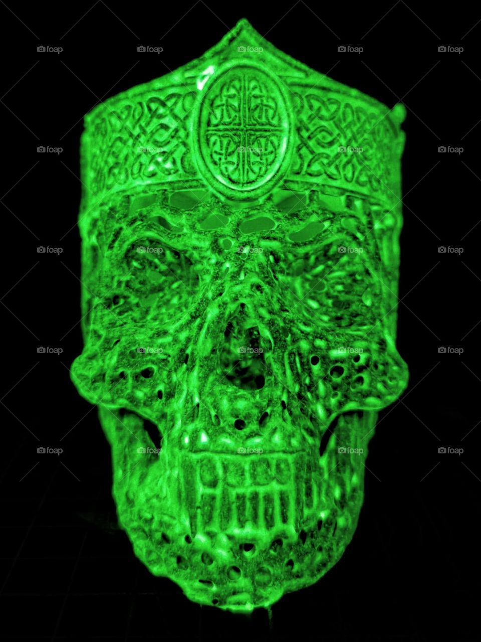 3D printed glow in the dark lattice skull with crown glowing green and black background