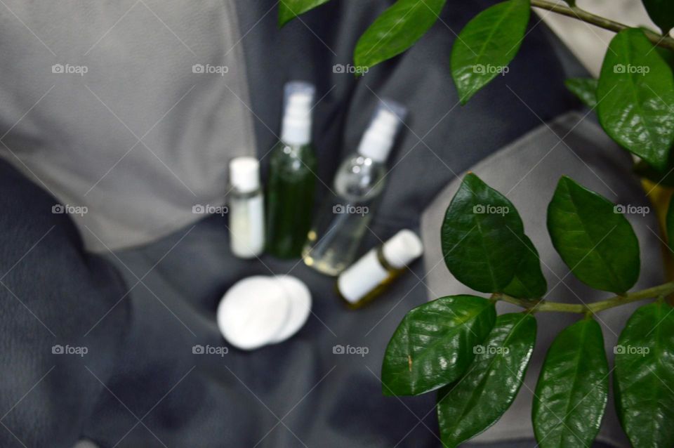 Jars with cream, shampoo and cosmetics on a background with green plants