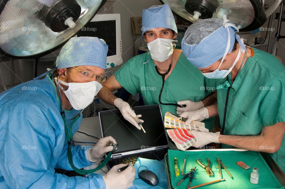 Three men in an emergency room operating on a computer