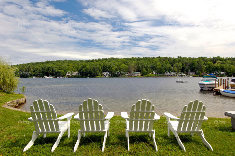 Four Adirondack chairs alongside the lake