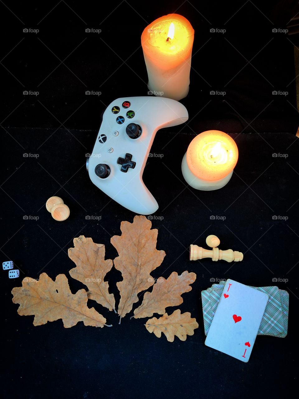 Games in the evening. Composition. Autumn oak leaves as pointers to popular games: dice, backgammon, gamepad, chess, cards. There are two burning candles nearby